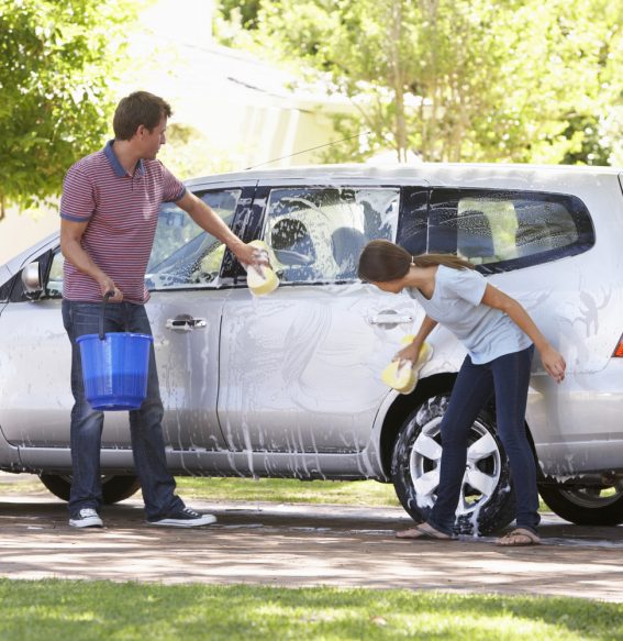 Dad spending time with daughter while washing the car